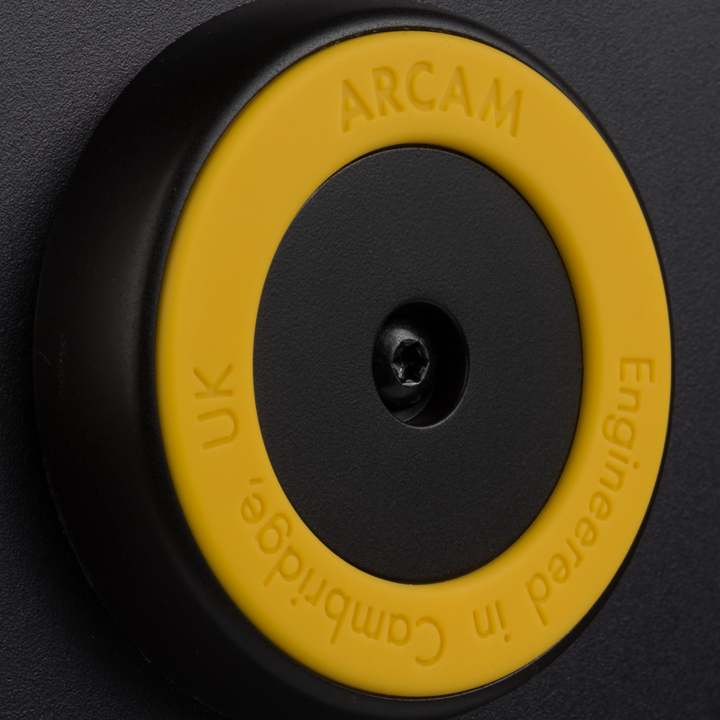 Close-up of a yellow and black component with 'Arcam' branding on a dark background