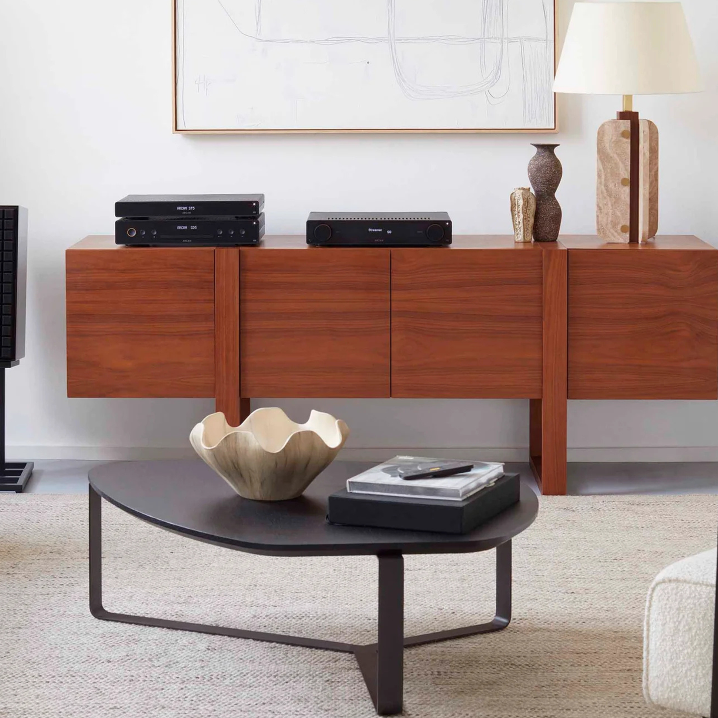 Wooden entertainment console with electronic devices and decor items in a living room setting.