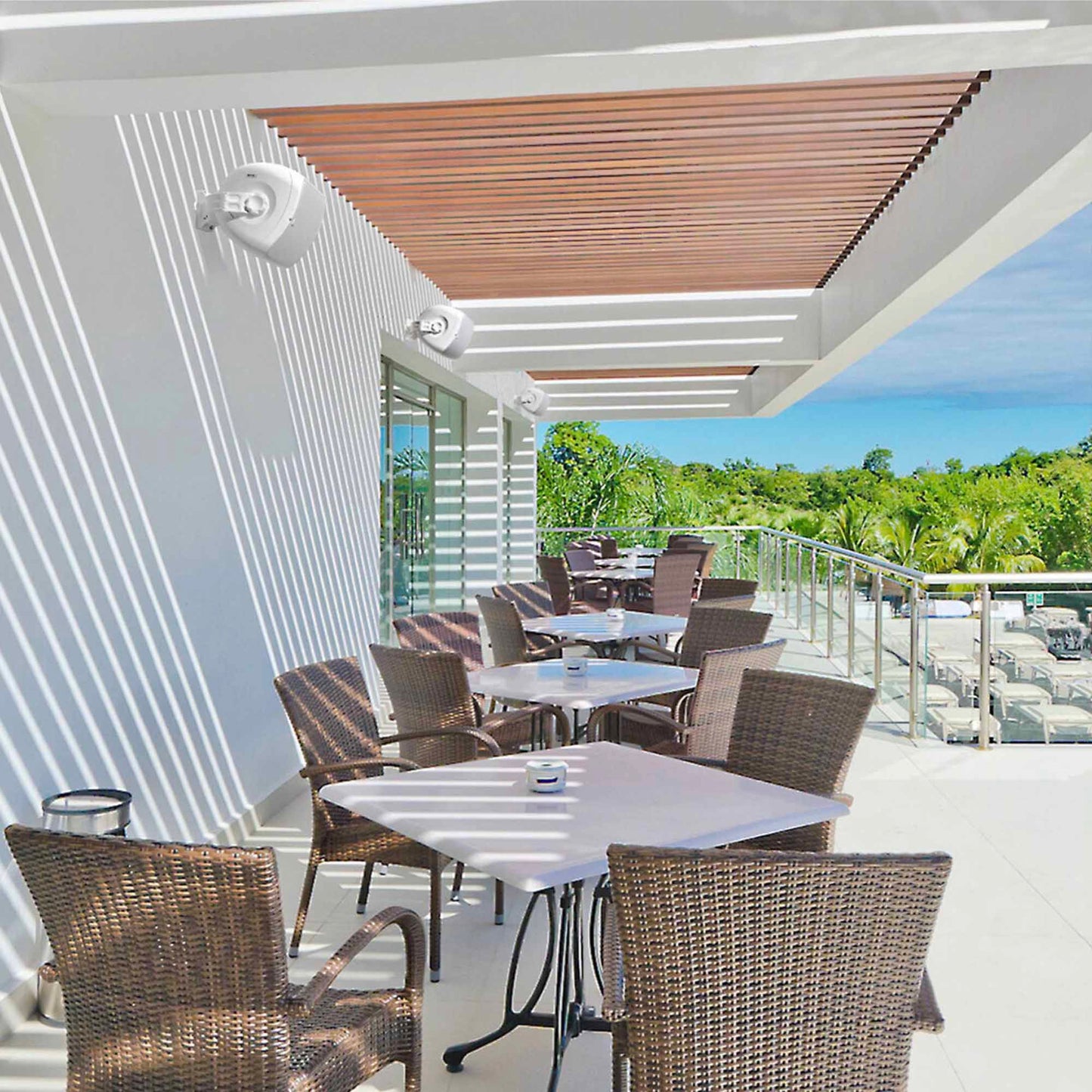 Outdoor patio area with tables and chairs under a pergola on a sunny day.