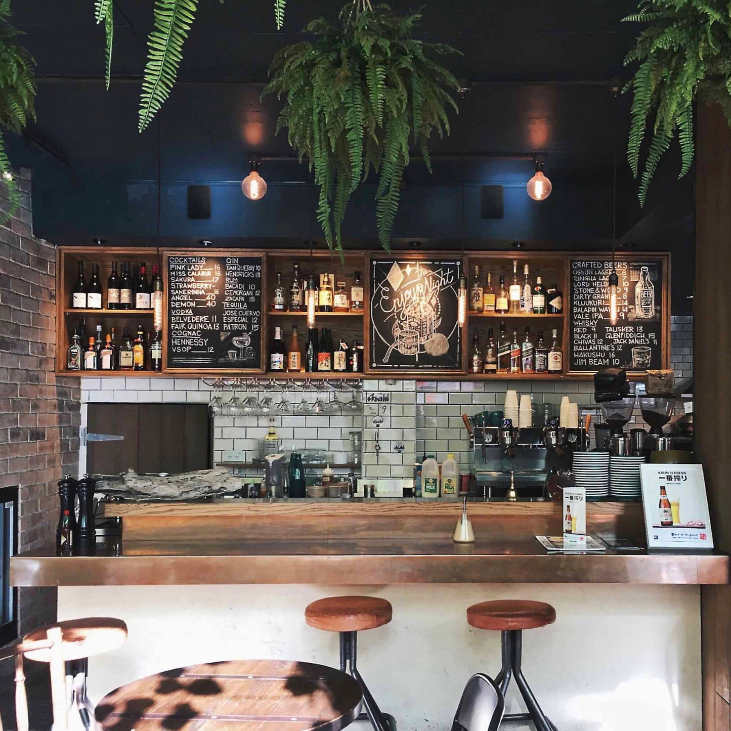 Bar interior with wooden counter, stools, and shelves with bottles and glasses.