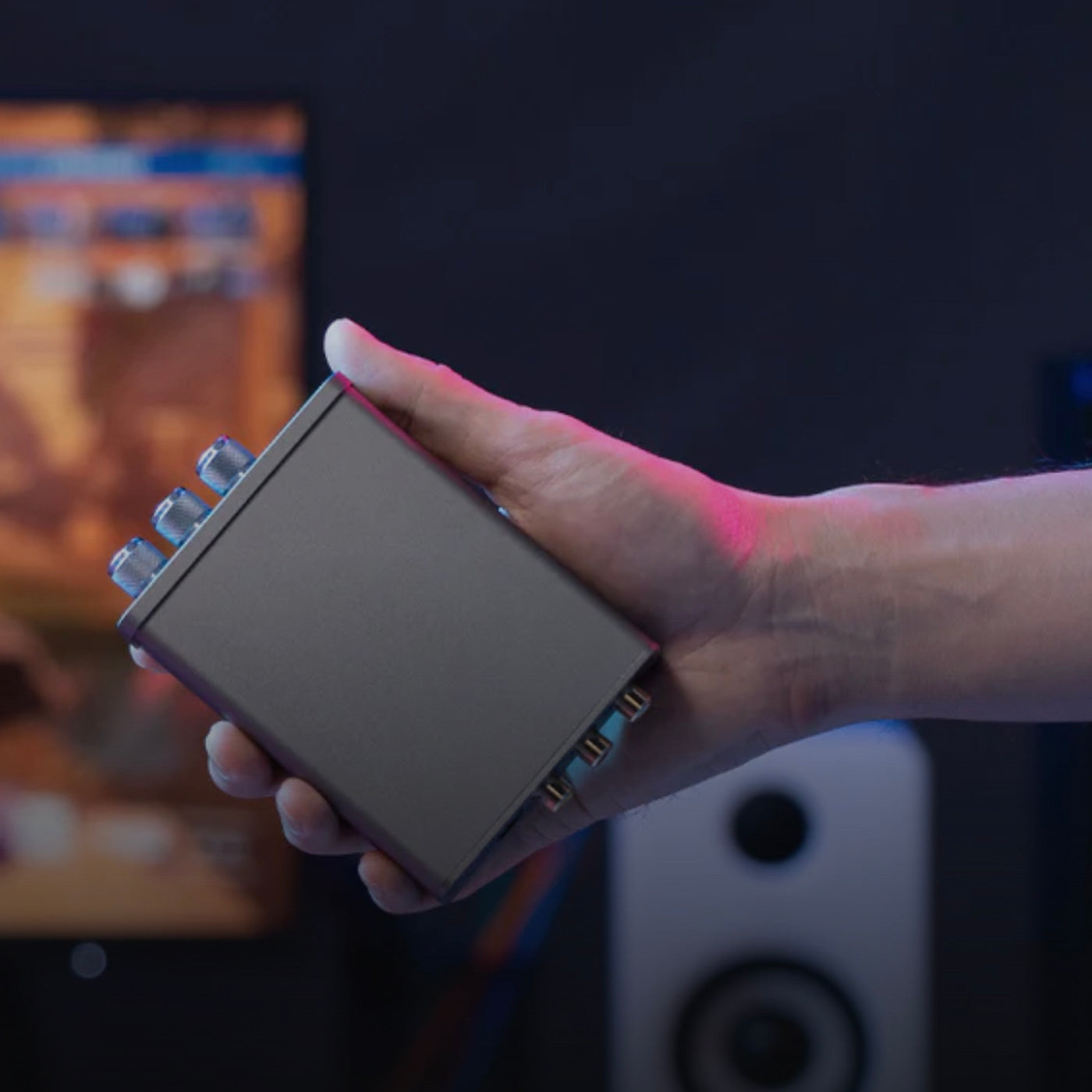 Hand holding a small electronic device with a blurred background