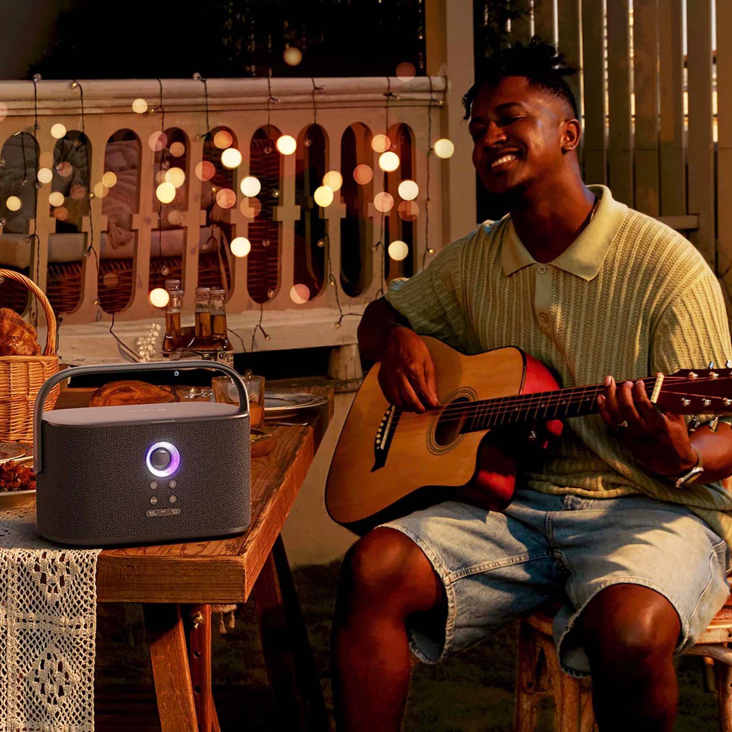 Ikarao speaker on table with man playing guitar