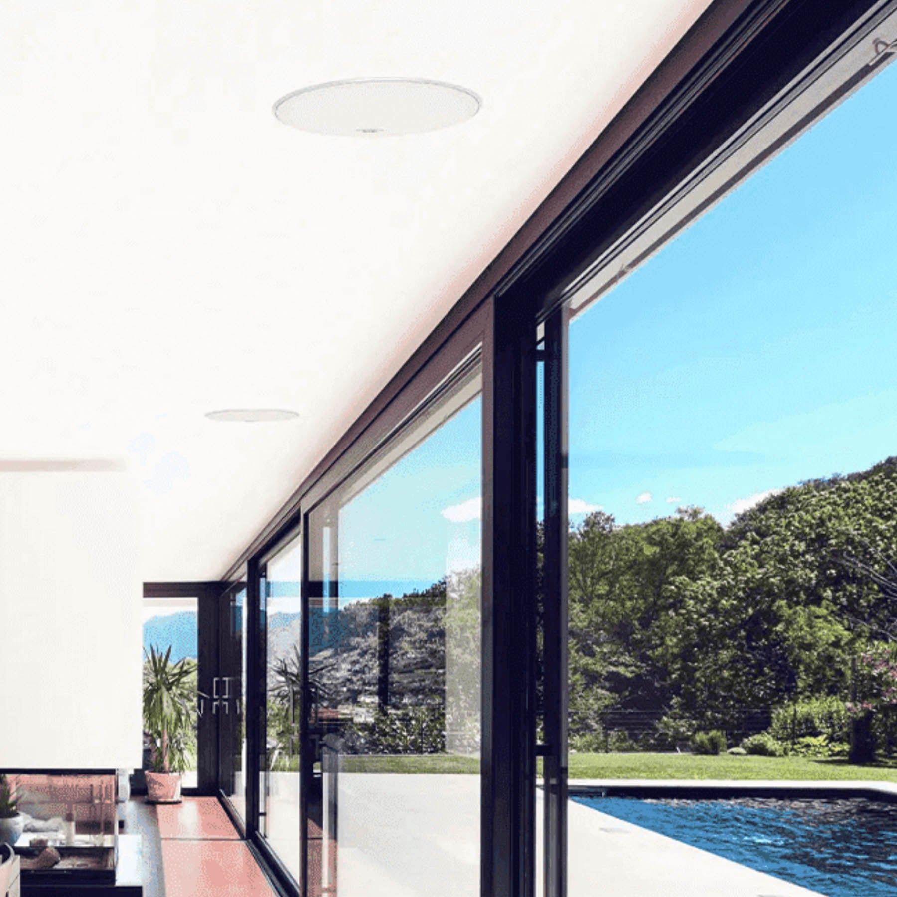 Modern interior with large glass doors leading to a pool and garden view