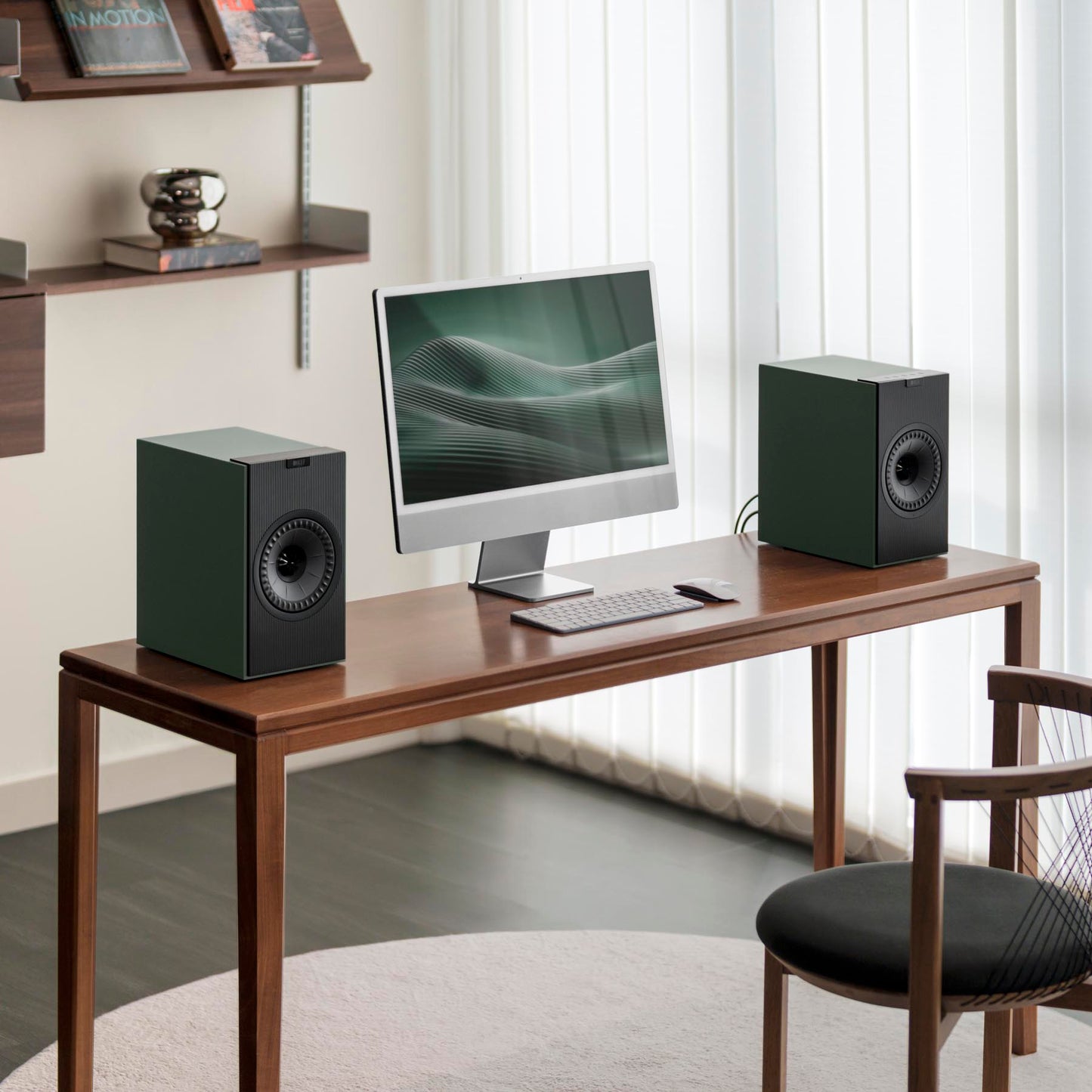 Modern home office setup with a desk, computer monitor, keyboard, and speakers.