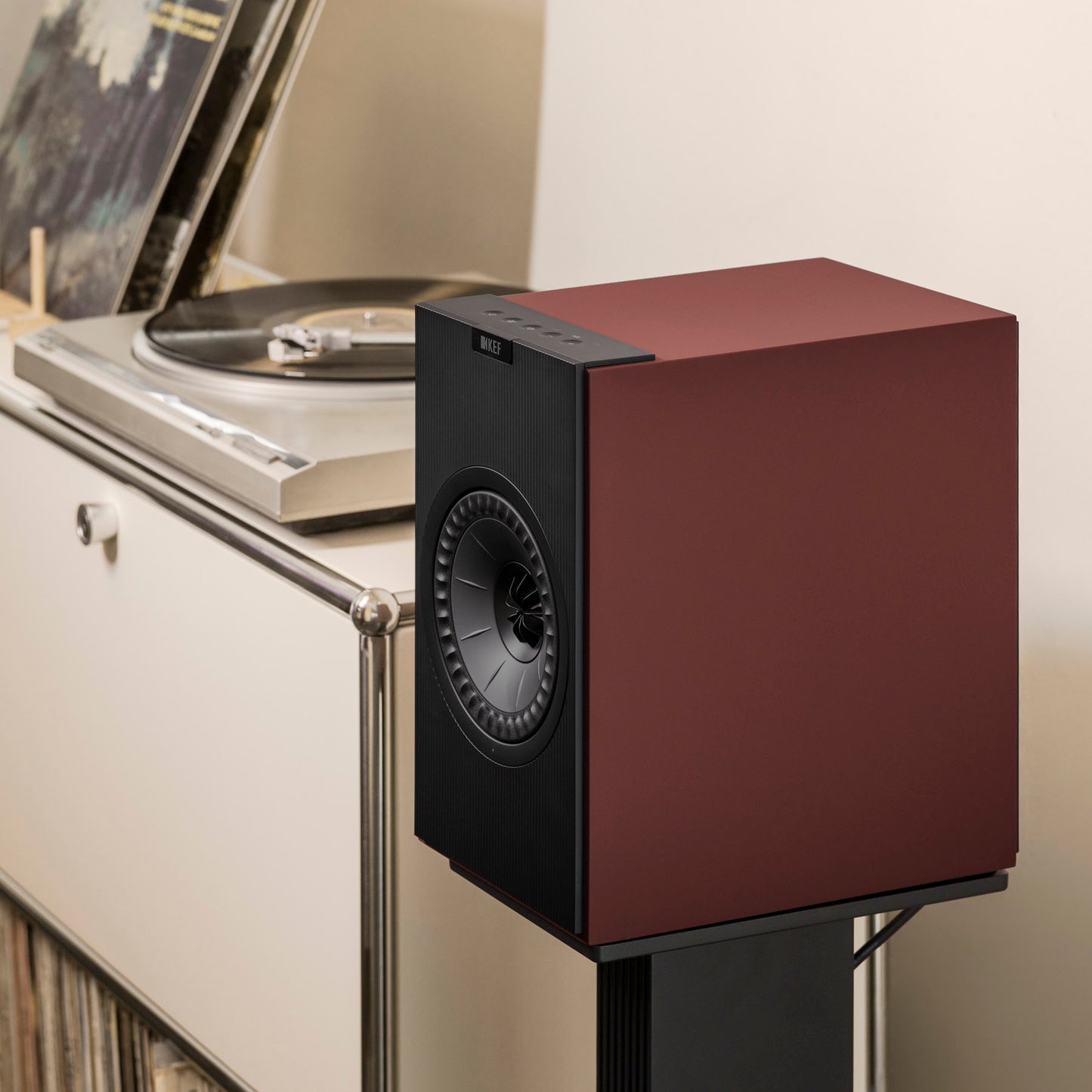 KEF Coda W Speaker in Vintage Burgundy next to white cabinet with turntable