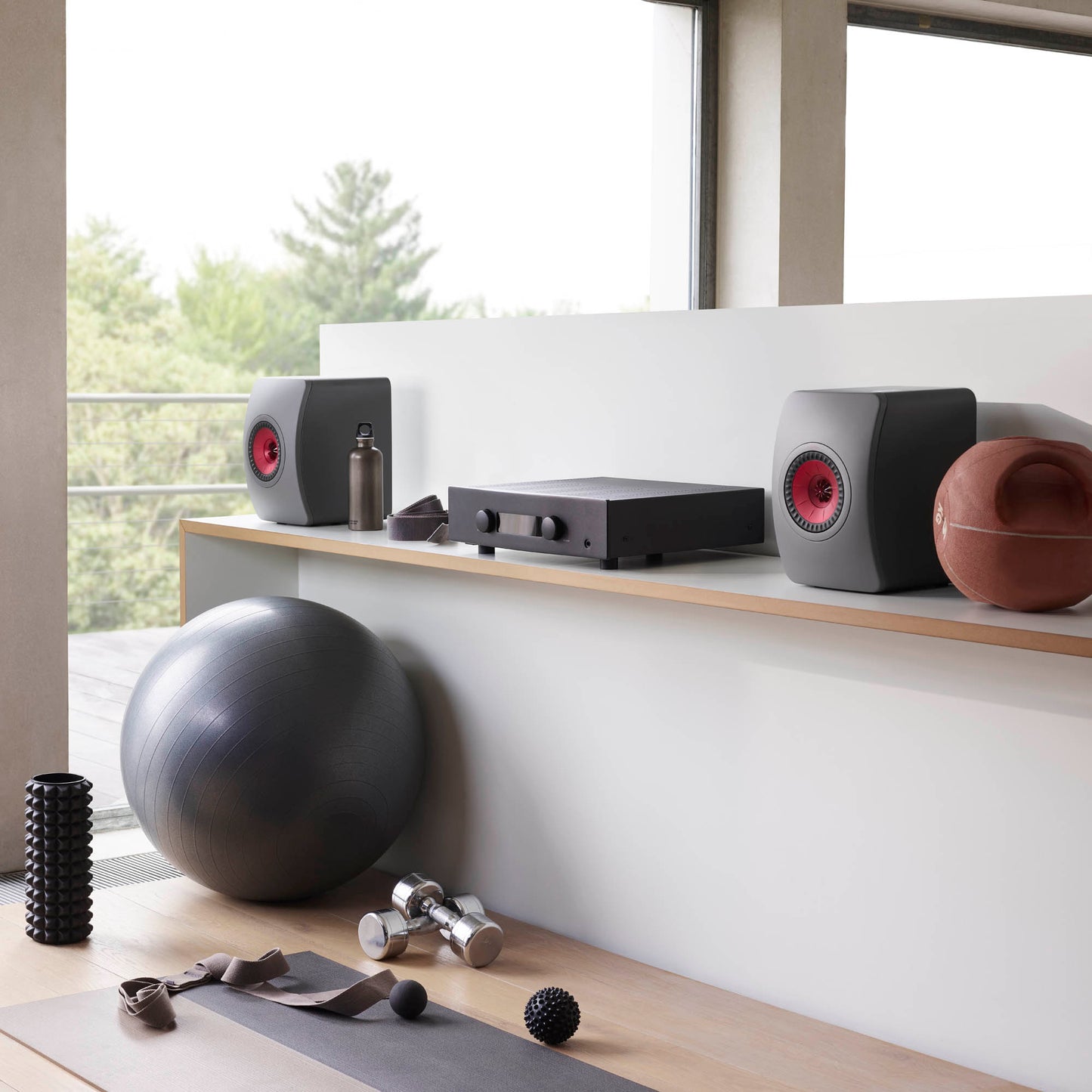 KEF LS50 Meta Bookshelf Speakers in Grey finish on bench with exercise equipment on the floor