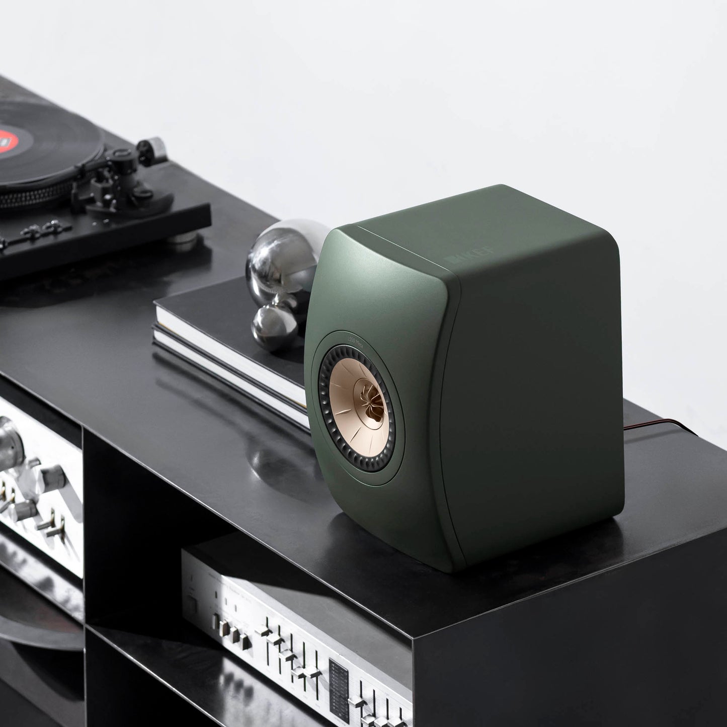 Green speaker on a turntable setup with vinyl records and audio equipment.