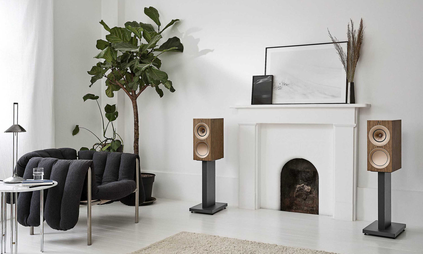 A pair of KEF R3 Meta speakers in wood next to fireplace.