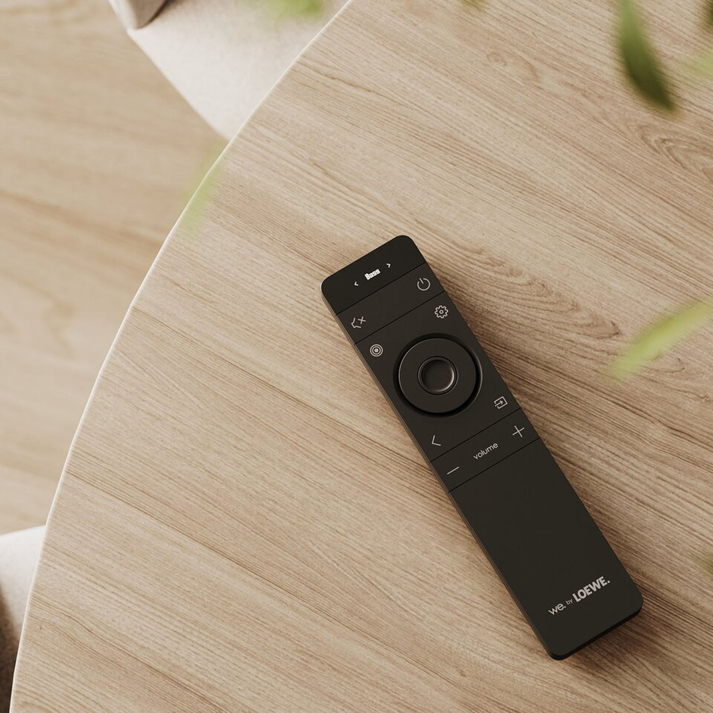 Black remote control on a wooden surface with 'Loewe' branding.