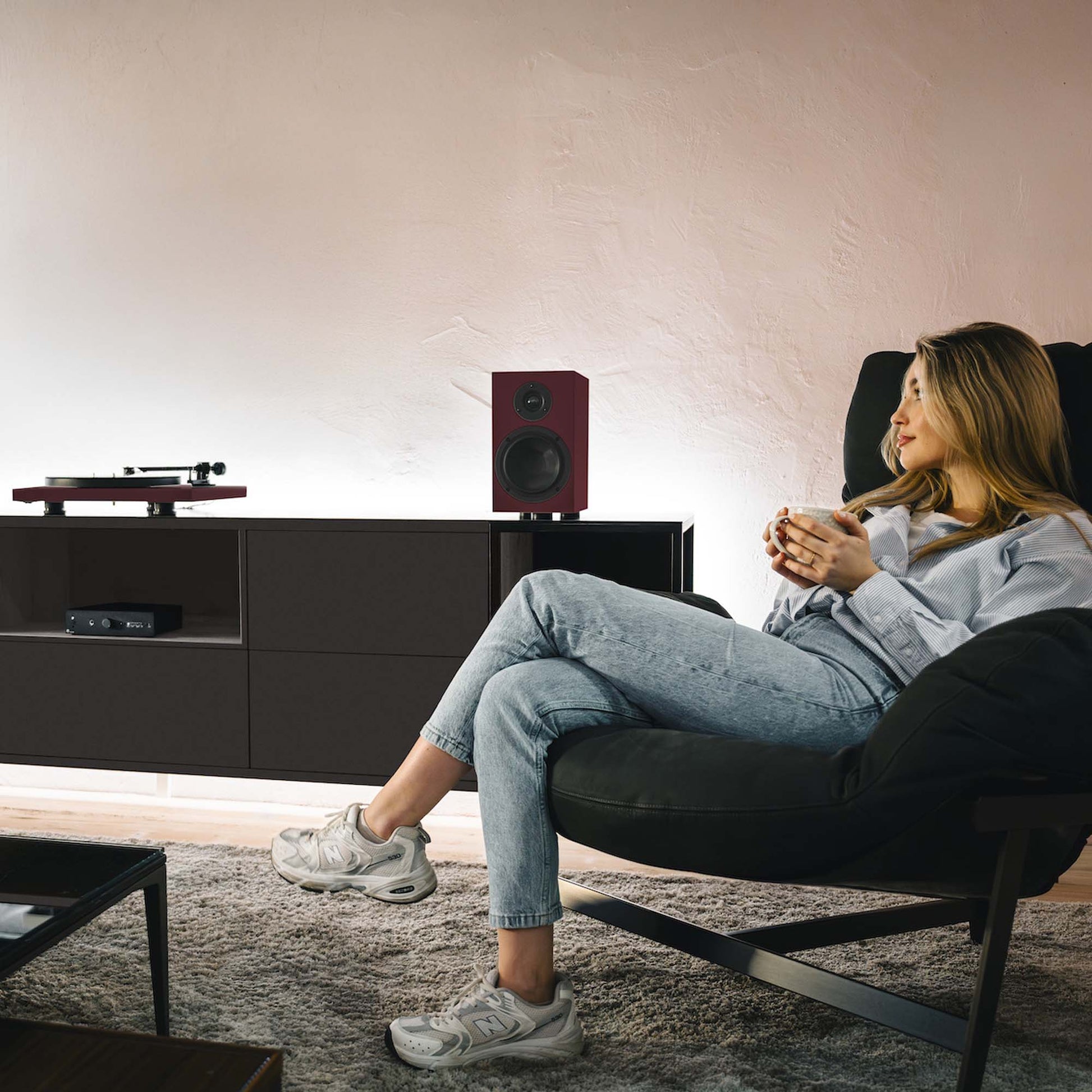 Woman sitting in a modern living room with a turntable and speakers.