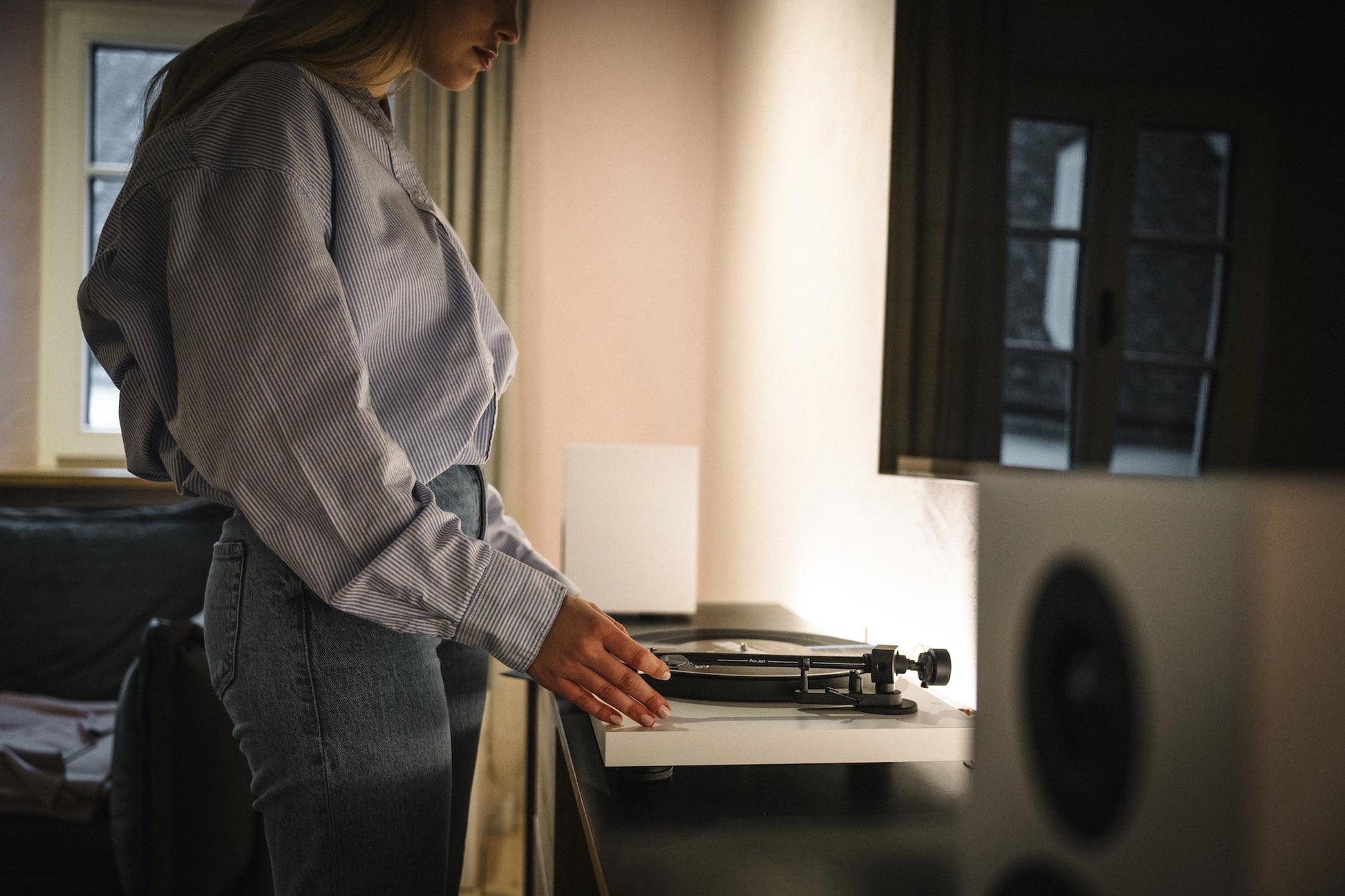 Person interacting with a record player in a room with soft lighting