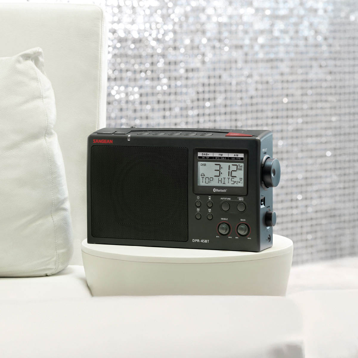 Black radio with digital display on a white surface with a decorative background