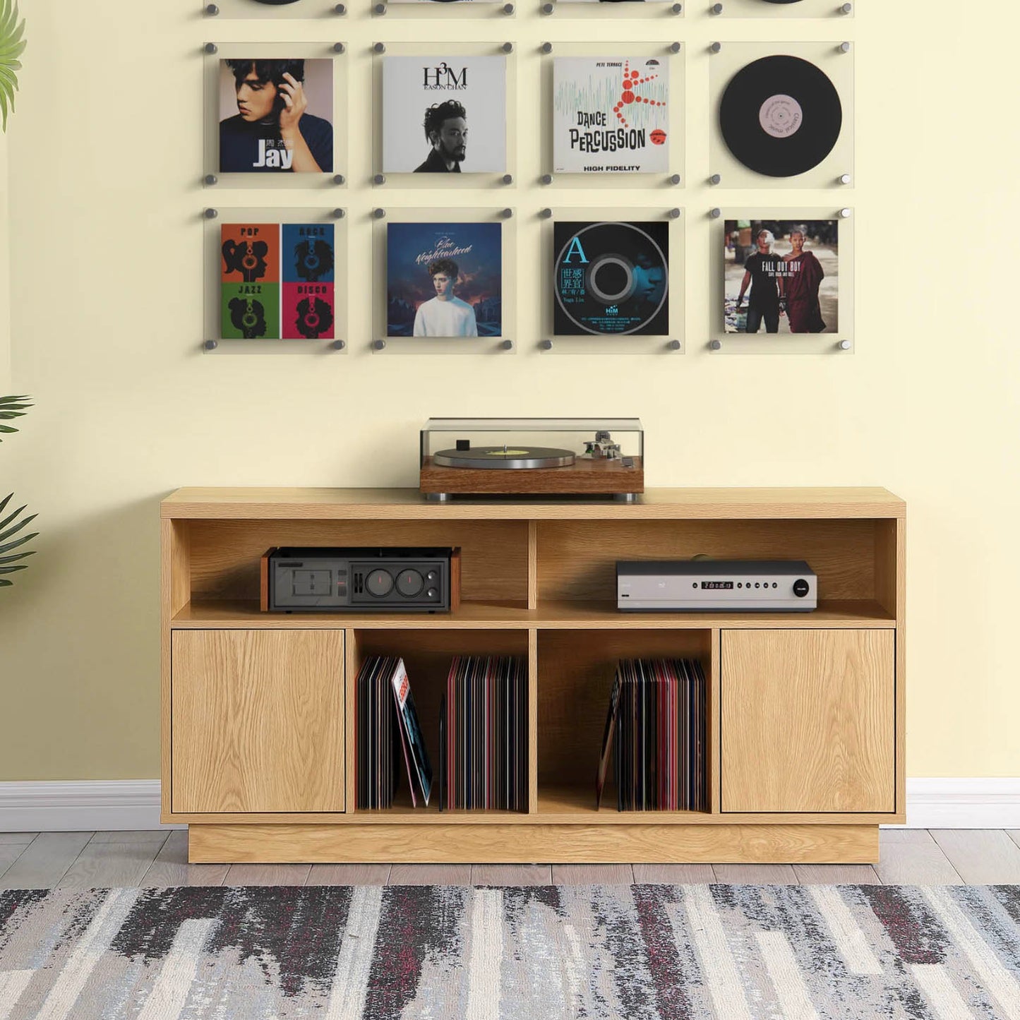 Wooden Tauris Edison 1400 Media Cabinet with vinyl records and a turntable against a wall with framed records.