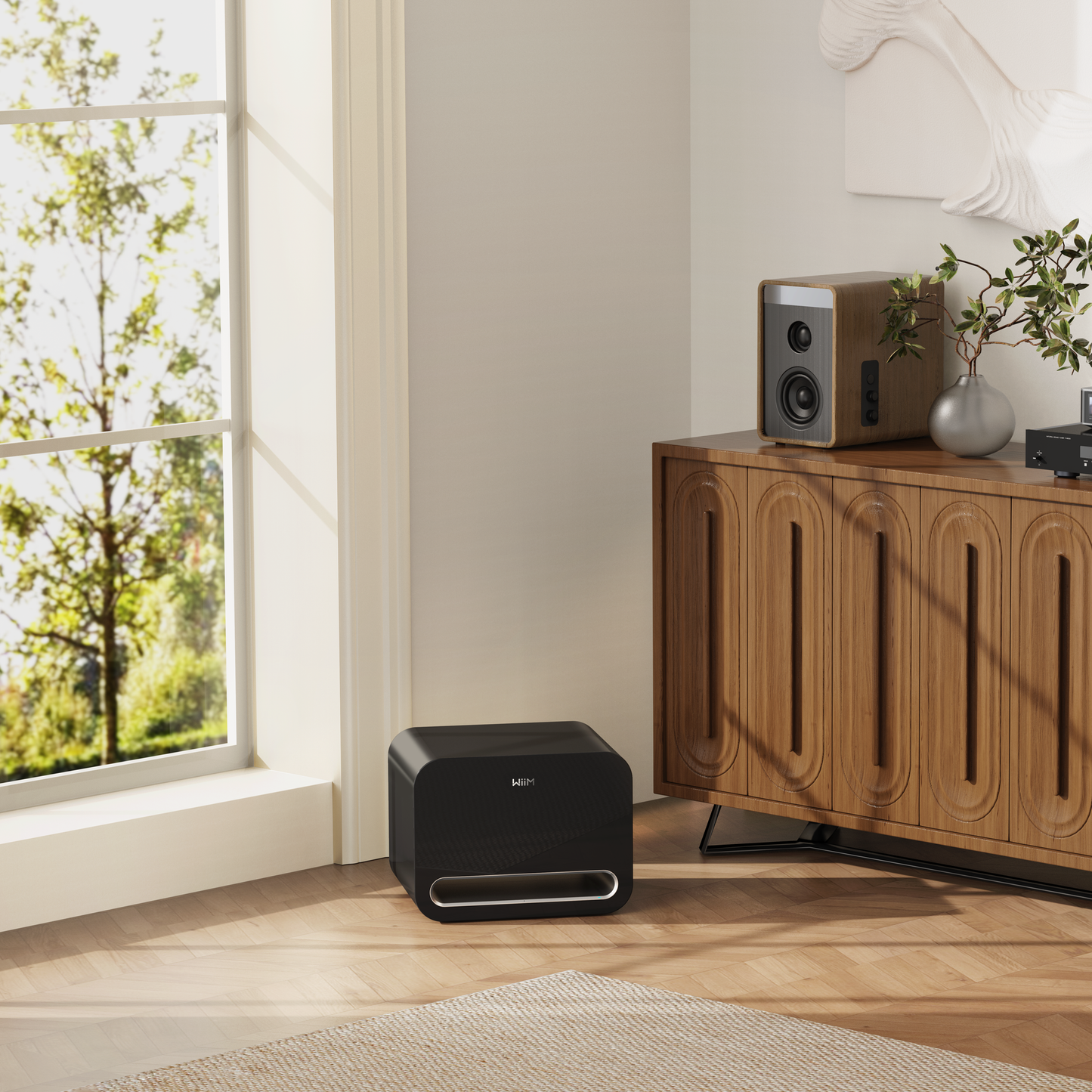 Black audio subwoofer on a wooden floor with a window and wooden cabinet in the background
