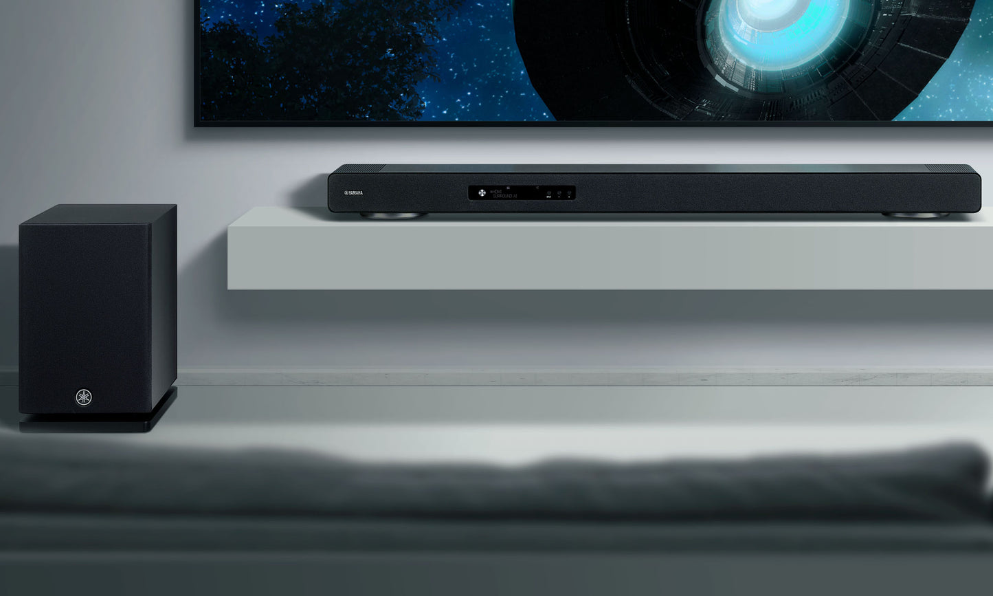 Soundbar system with subwoofer on a shelf in front of a television displaying a space-themed wallpaper.