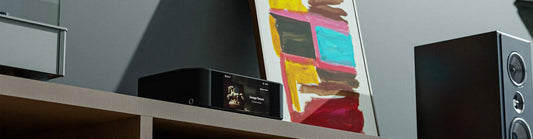 Bluesound unit sitting on cabinet next to speaker
