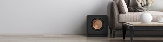 wall with black subwoofer, table and couch