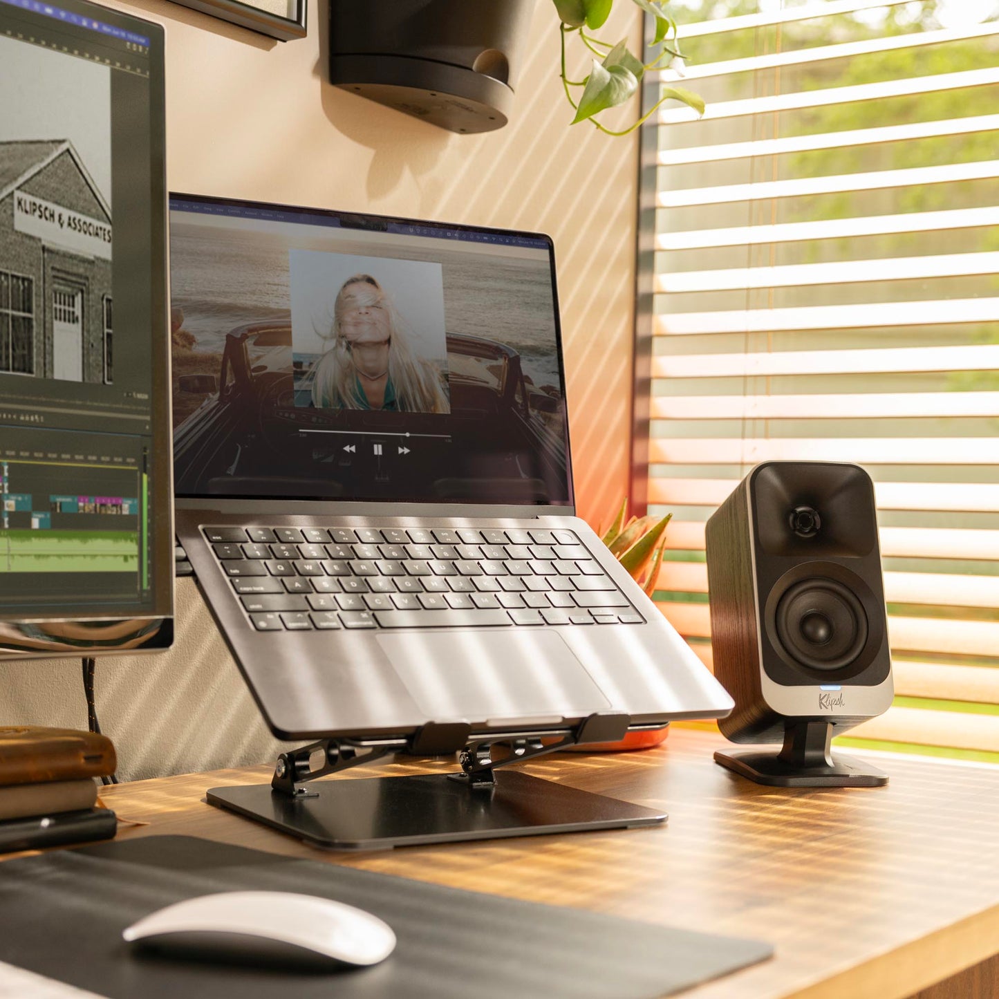 Laptop on a stand with two monitors, speakers, and a mouse on a desk.