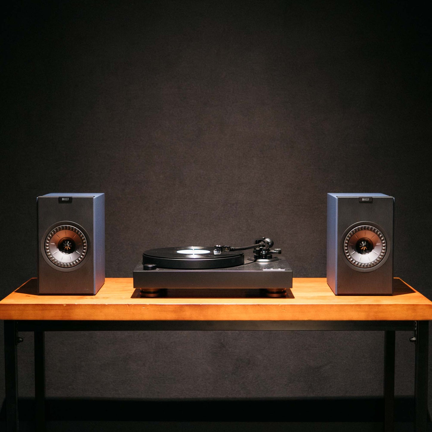 Turntable with speakers on a wooden table against a dark background