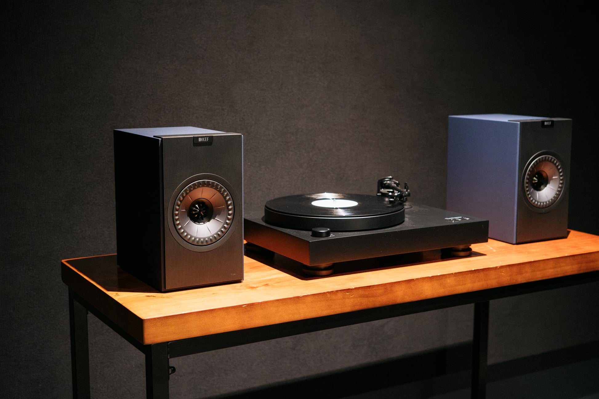 Turntable with two speakers on a wooden table against a dark background