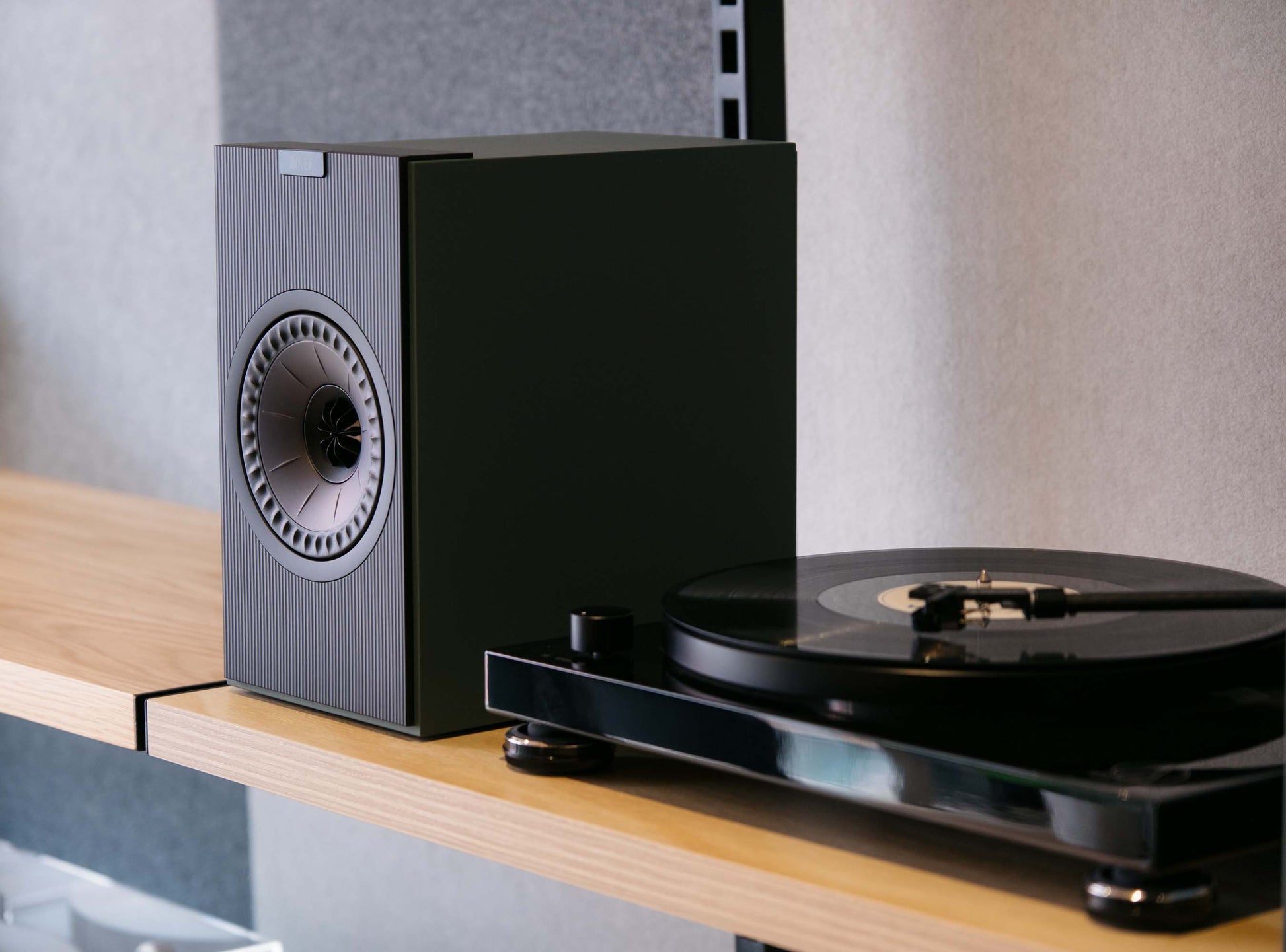 Black turntable with speaker on a wooden surface