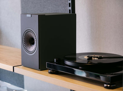 Black turntable with speaker on a wooden surface