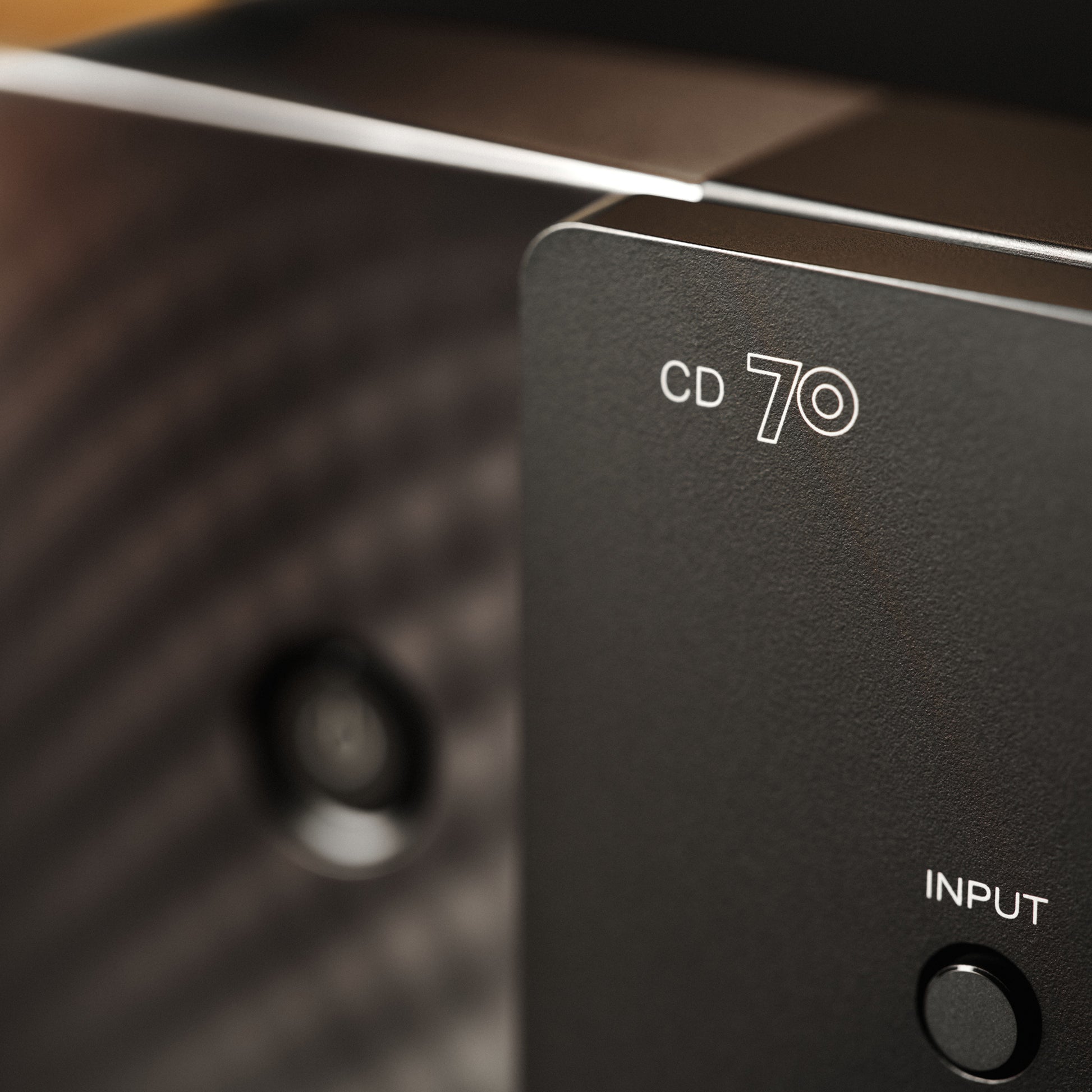 Close-up of a black electronic device panel with white text reading 'CD 70' and 'INPUT' next to a round button.
