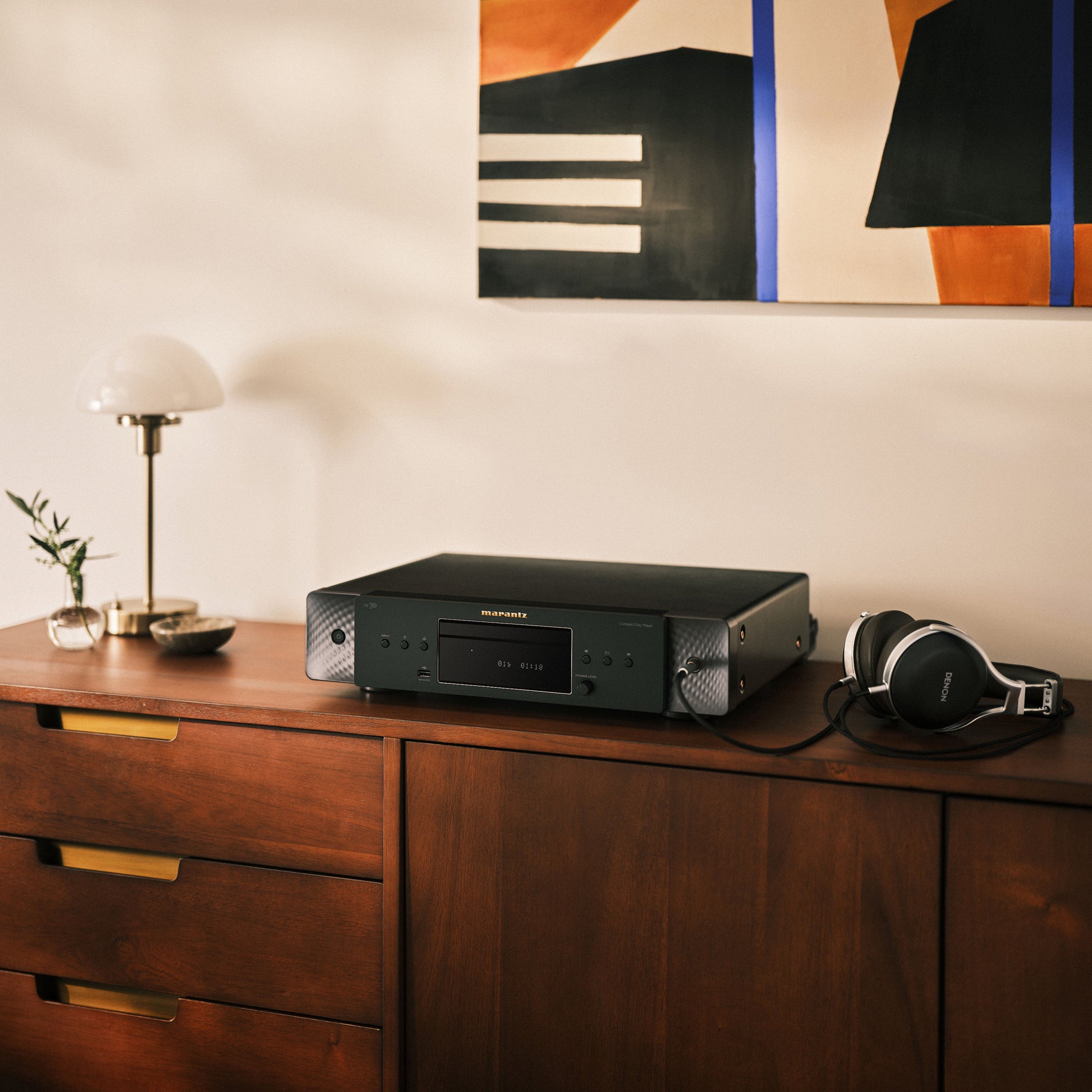 Black Marantz CD 70 CD Player sitting on dark timber cabinet with headphones next to it.