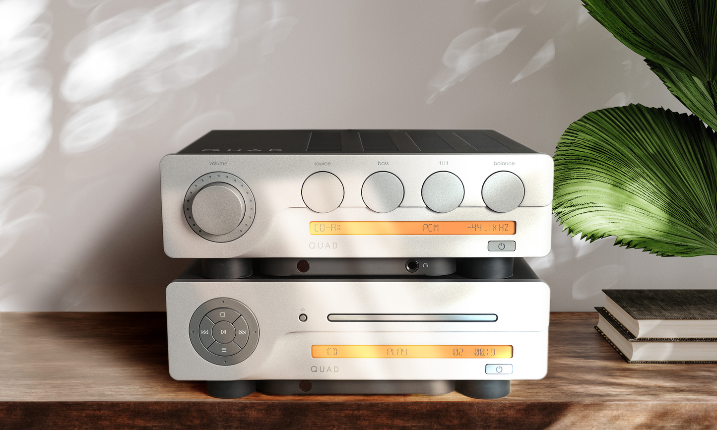 Quad Audio equipment on a wooden surface with a plant in the background