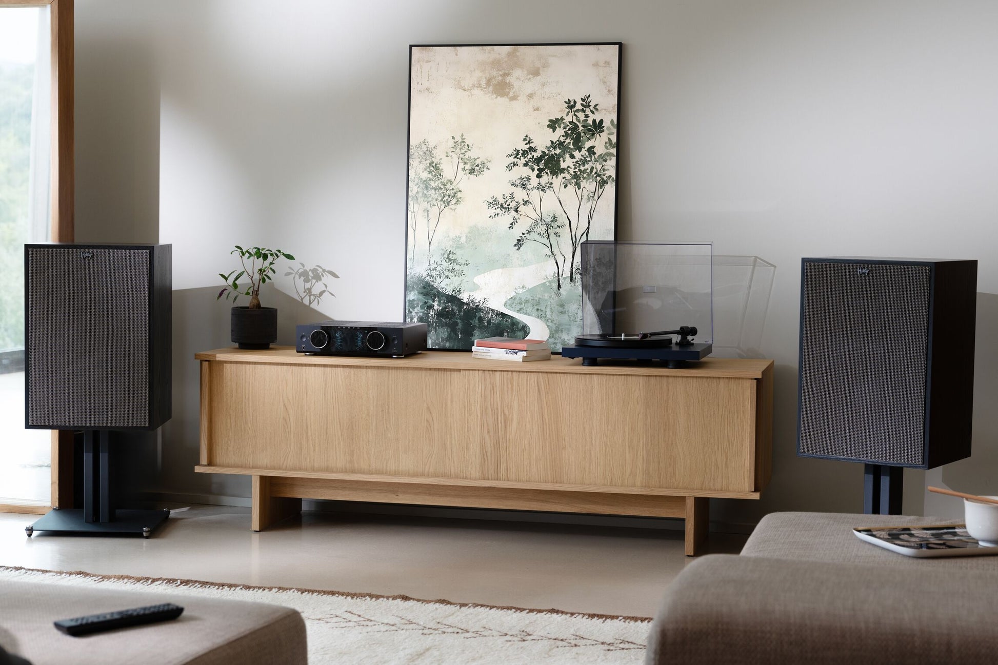 Living room with wooden entertainment console, speakers, and a painting on the wall.