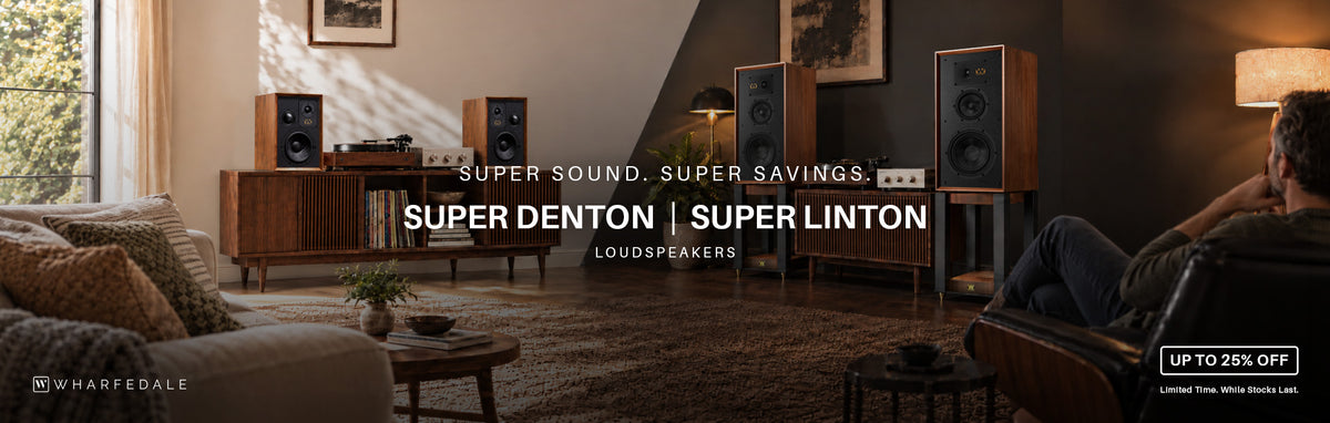 A lifestyle advertisement for Wharfedale Loudspeakers, showcasing the Super Denton and Super Linton models in a modern, cozy living room setting. 