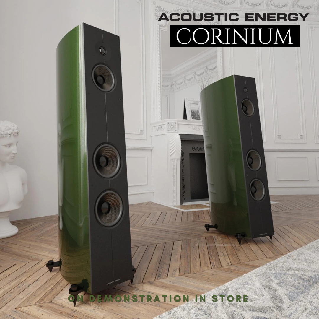 Two Acoustic Energy Corinium speakers in a room with a fireplace and marble statue.