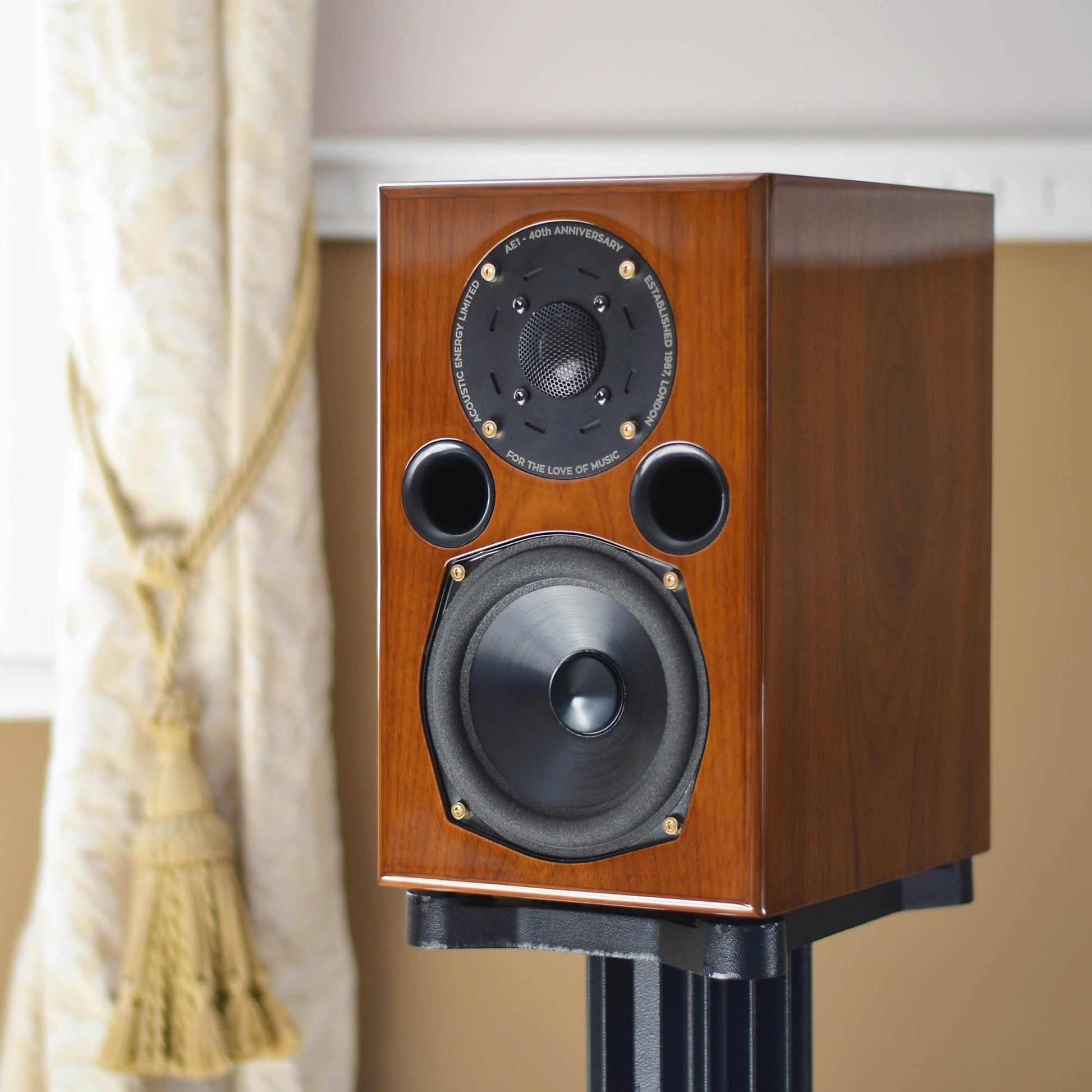 Walnut Acoustic Energy AE1 40th Anniversary Edition on a stand against a neutral background