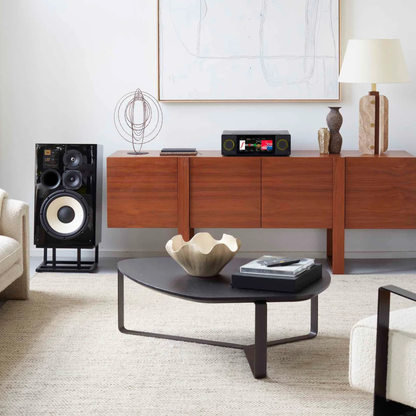 Arcam SA45 Streaming Integrated Amplifier on timber cabinet in living room. Coffee table and artwork on the wall.