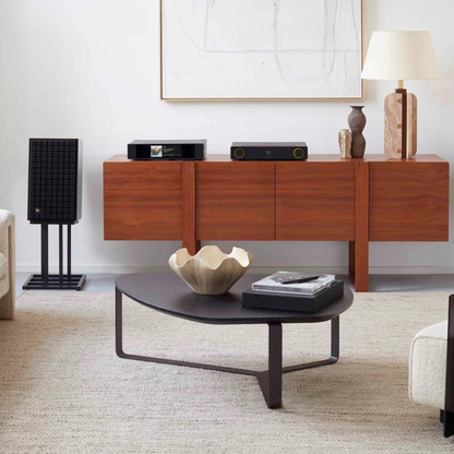 Modern living room with wooden console table, speakers, and decorative items.