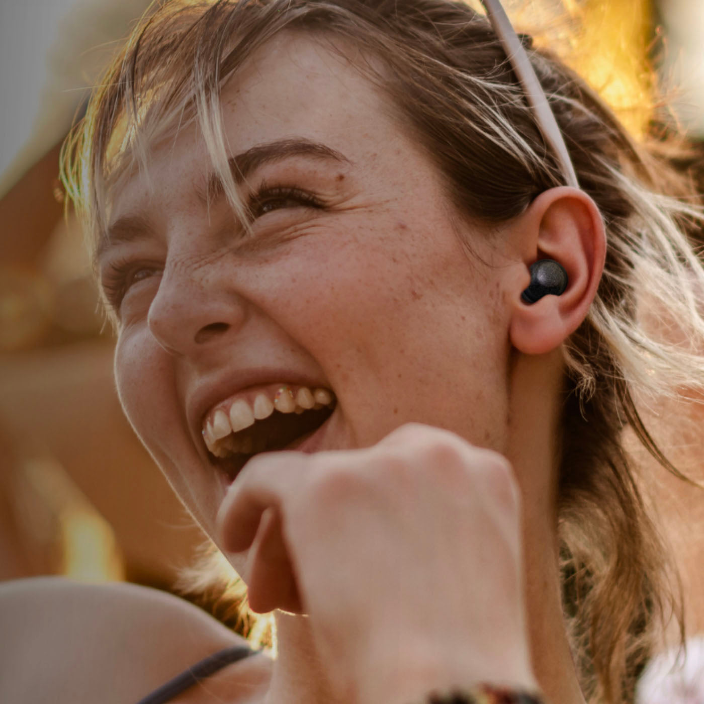 Woman wearing wireless earbuds with a blurred outdoor background