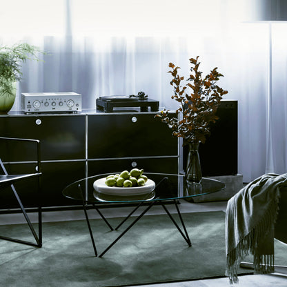 Modern living room with black furniture, a glass coffee table, and decorative elements.