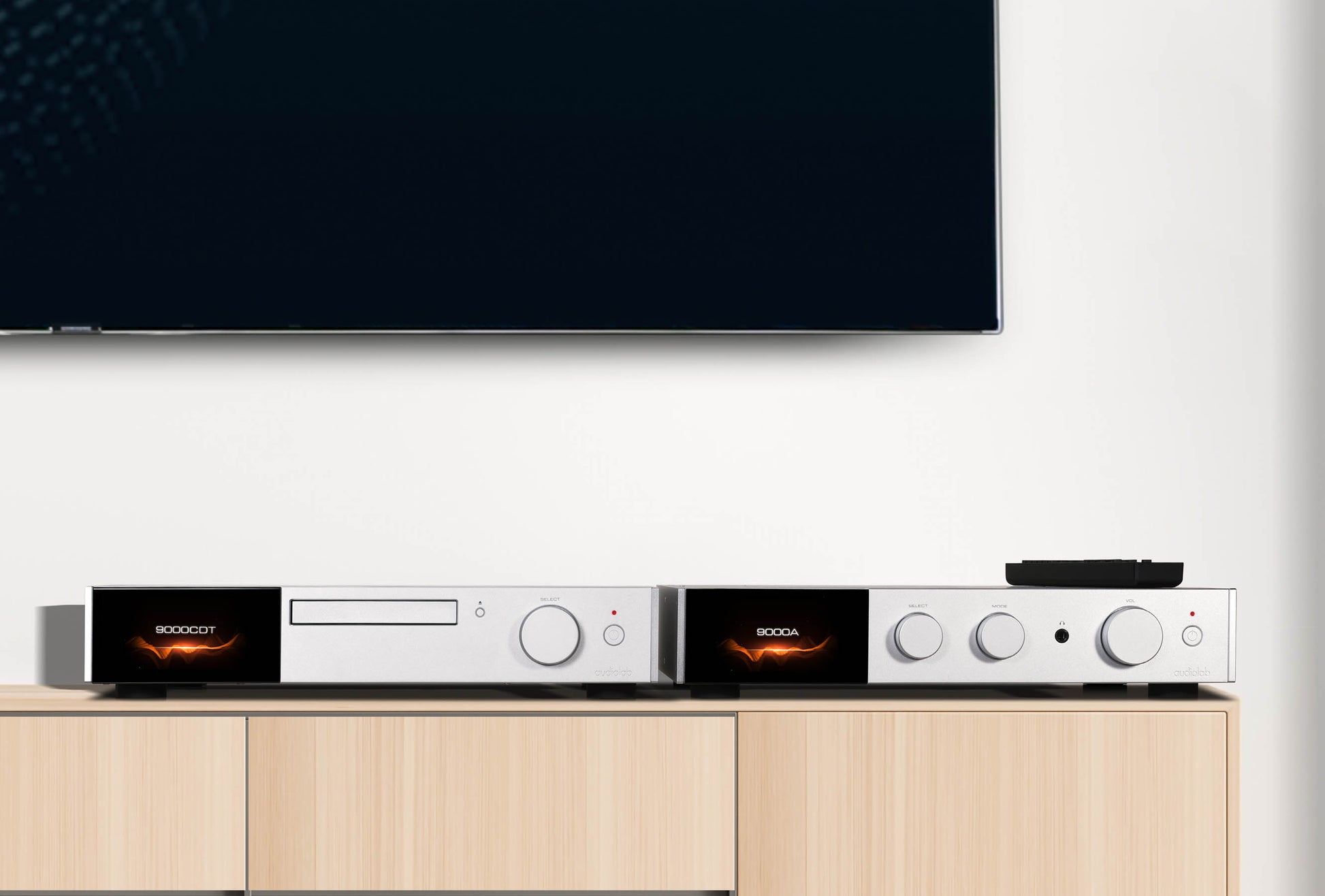 Audio equipment on a wooden cabinet with a television in the background