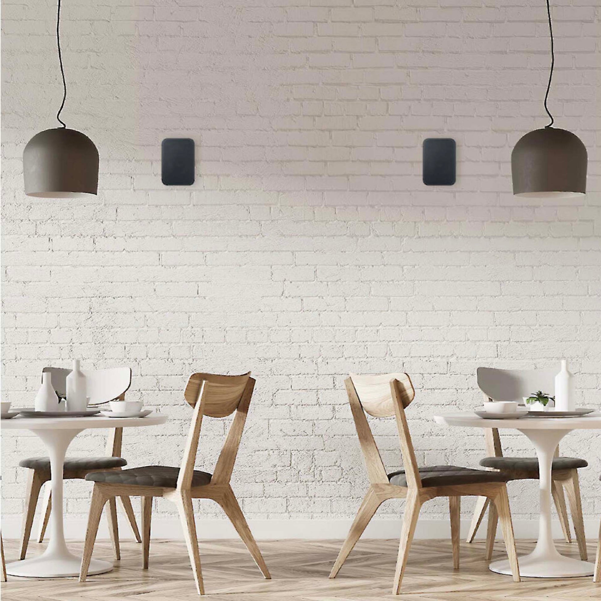 Dining area with wooden chairs and white tables against a white brick wall.