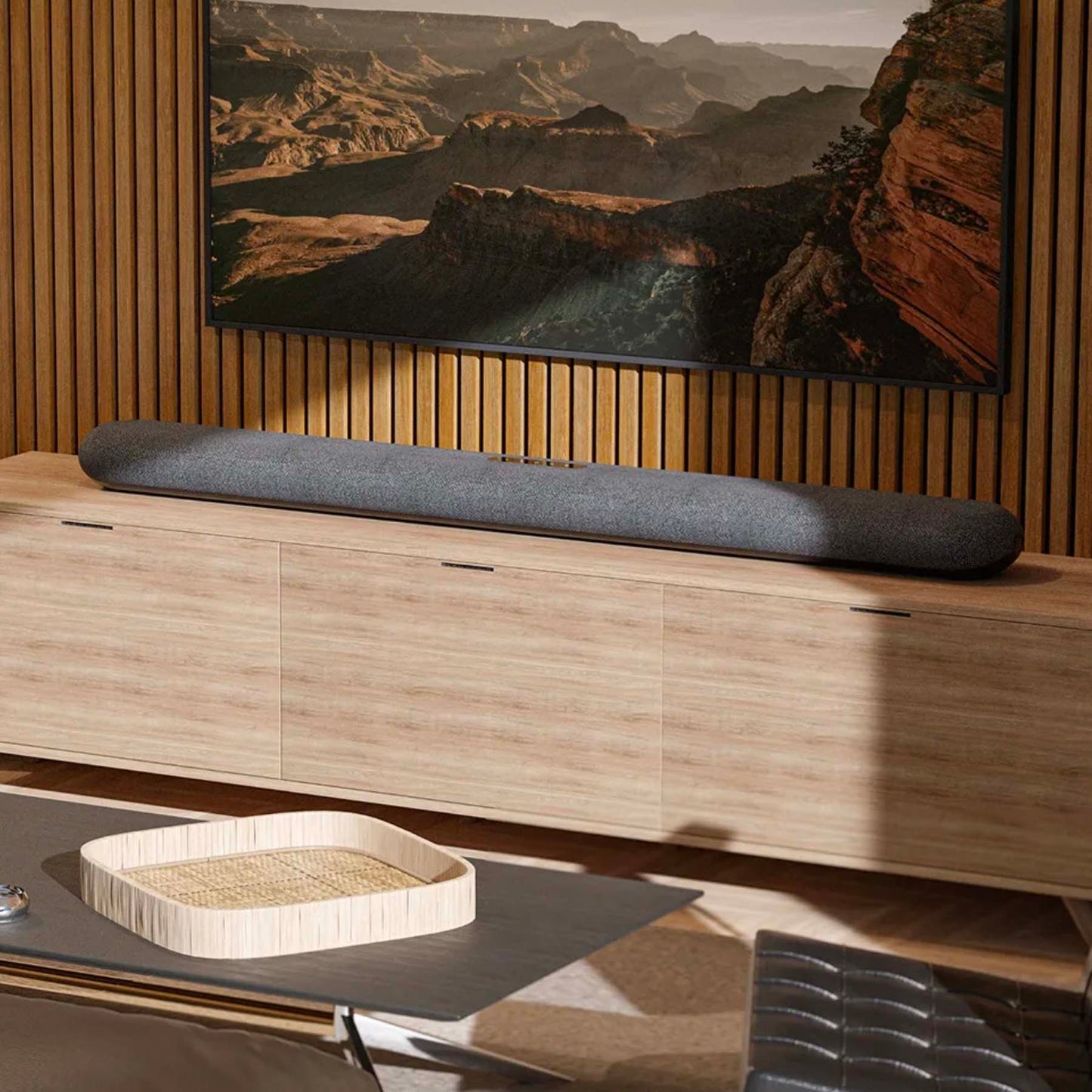 Bluesound Pulse Cinema Soundbar on tv cabinet with tv mounted on wall behind