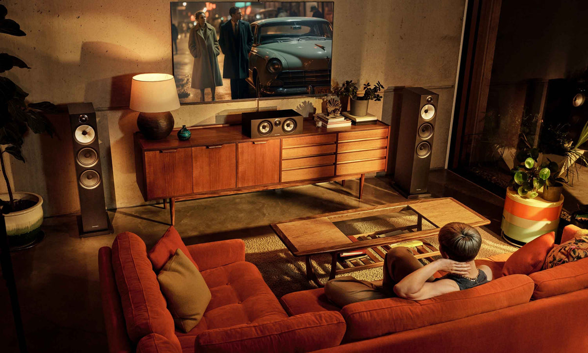 Living room with speaker system, terracota couch with couple watching a movie