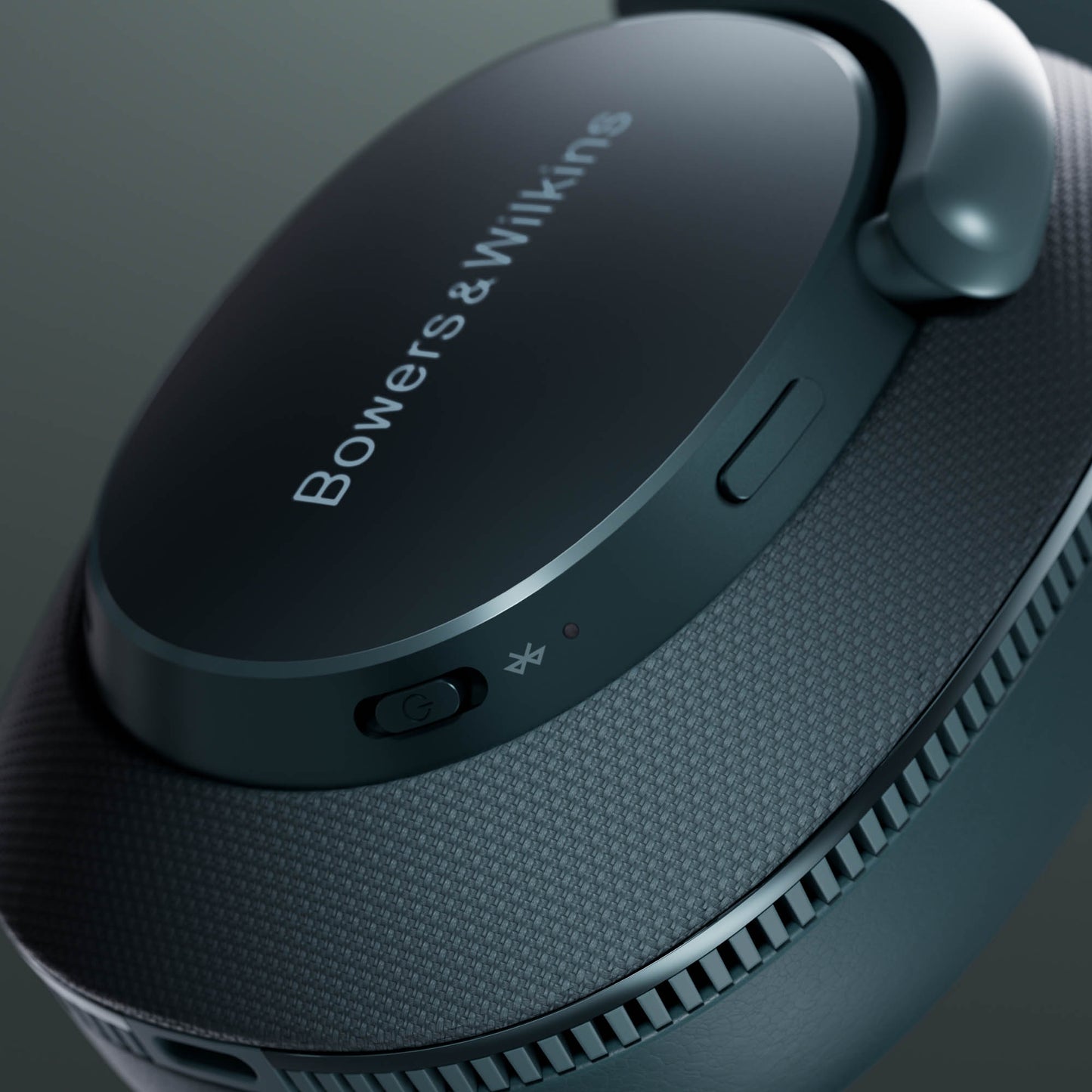 Close-up of Bowers & Wilkins headphones with bluetooth button on a dark background
