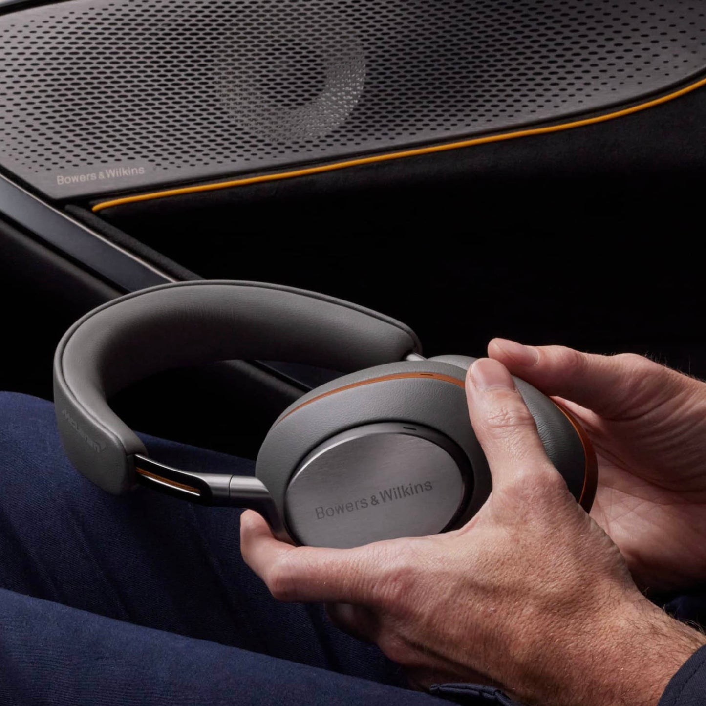 Person holding Bowers & Wilkins headphones with a car interior background
