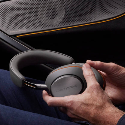 Person holding Bowers & Wilkins headphones with a car interior background