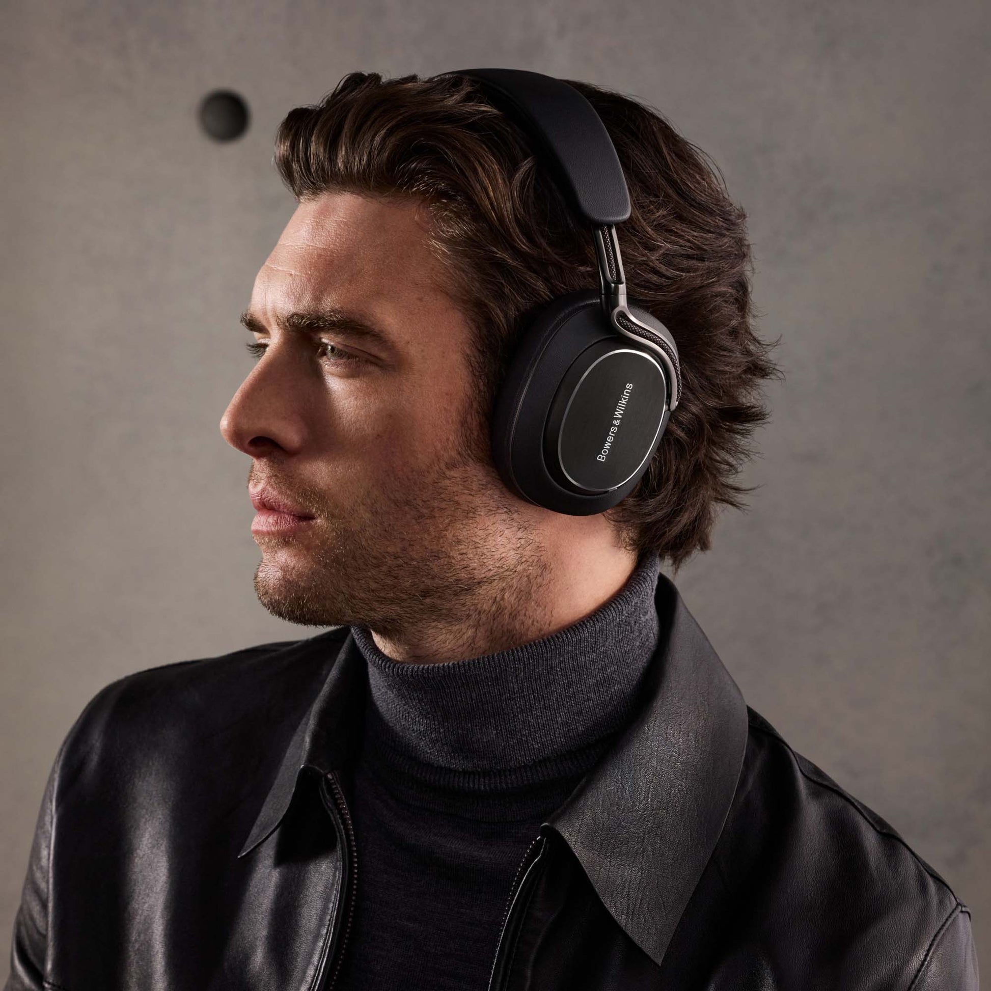 Man wearing black headphones against a gray background