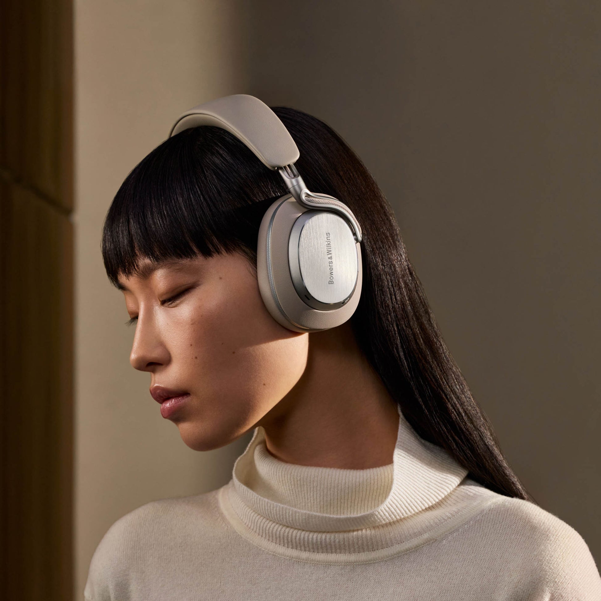 Woman wearing a pair of headphones against a neutral background