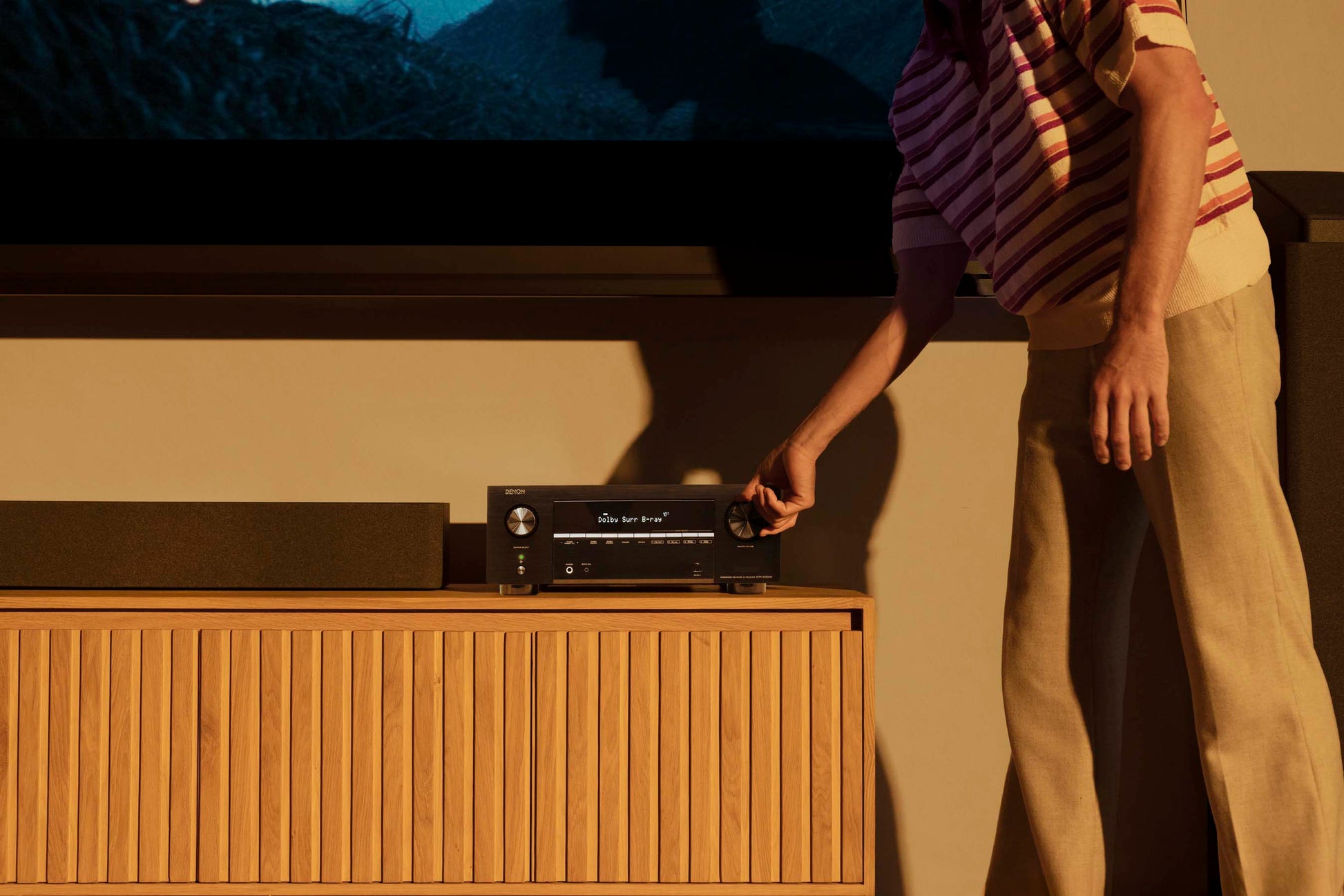 Person interacting with audio equipment in front of a television.