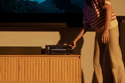Person interacting with audio equipment in front of a television.