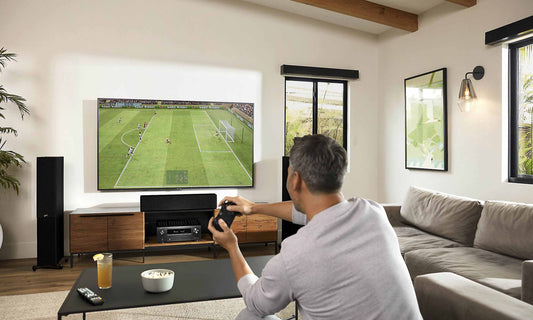 man playing video games in living room with tv and speakers
