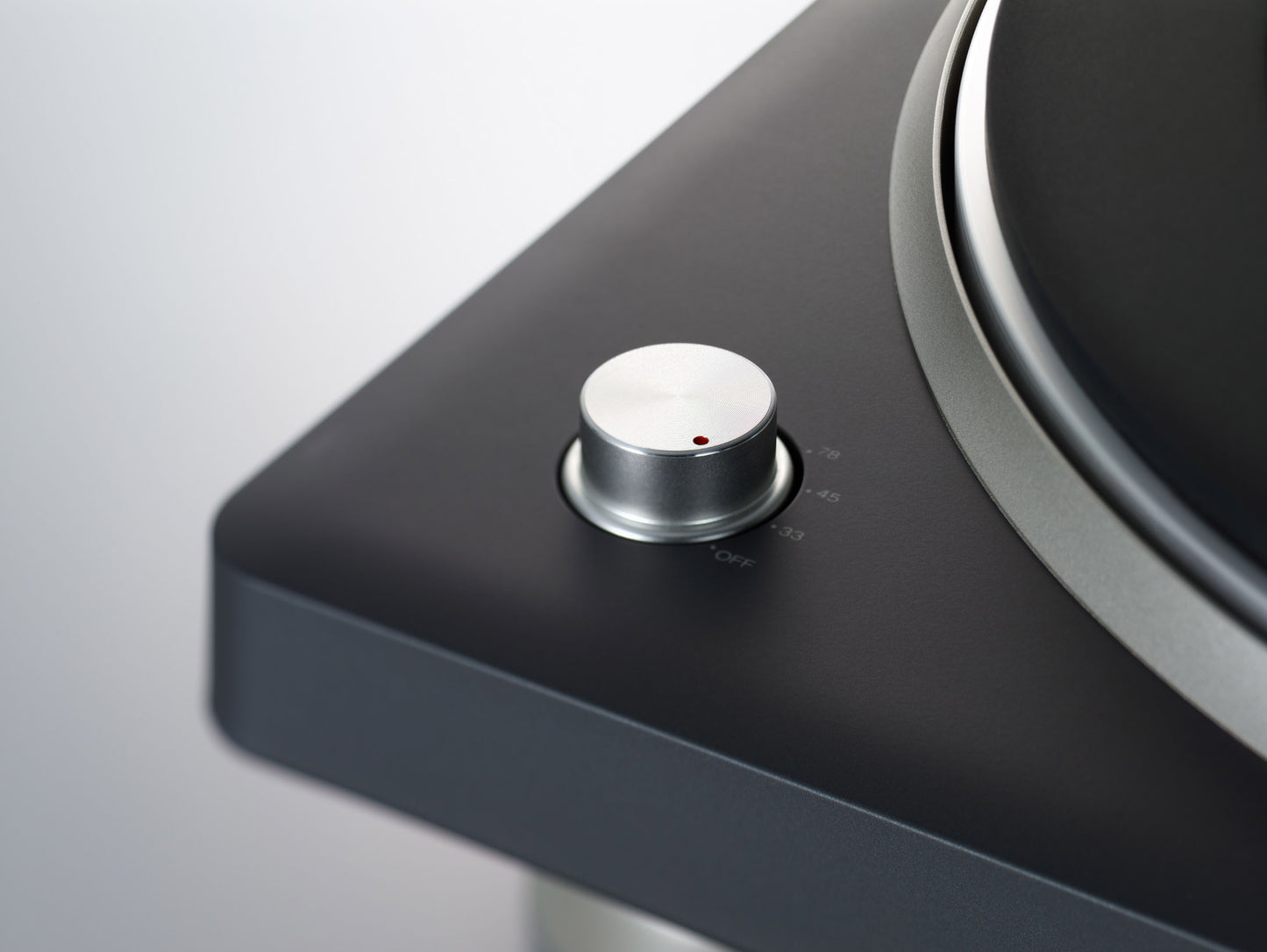 Close-up of a turntable with a control knob on a gray background